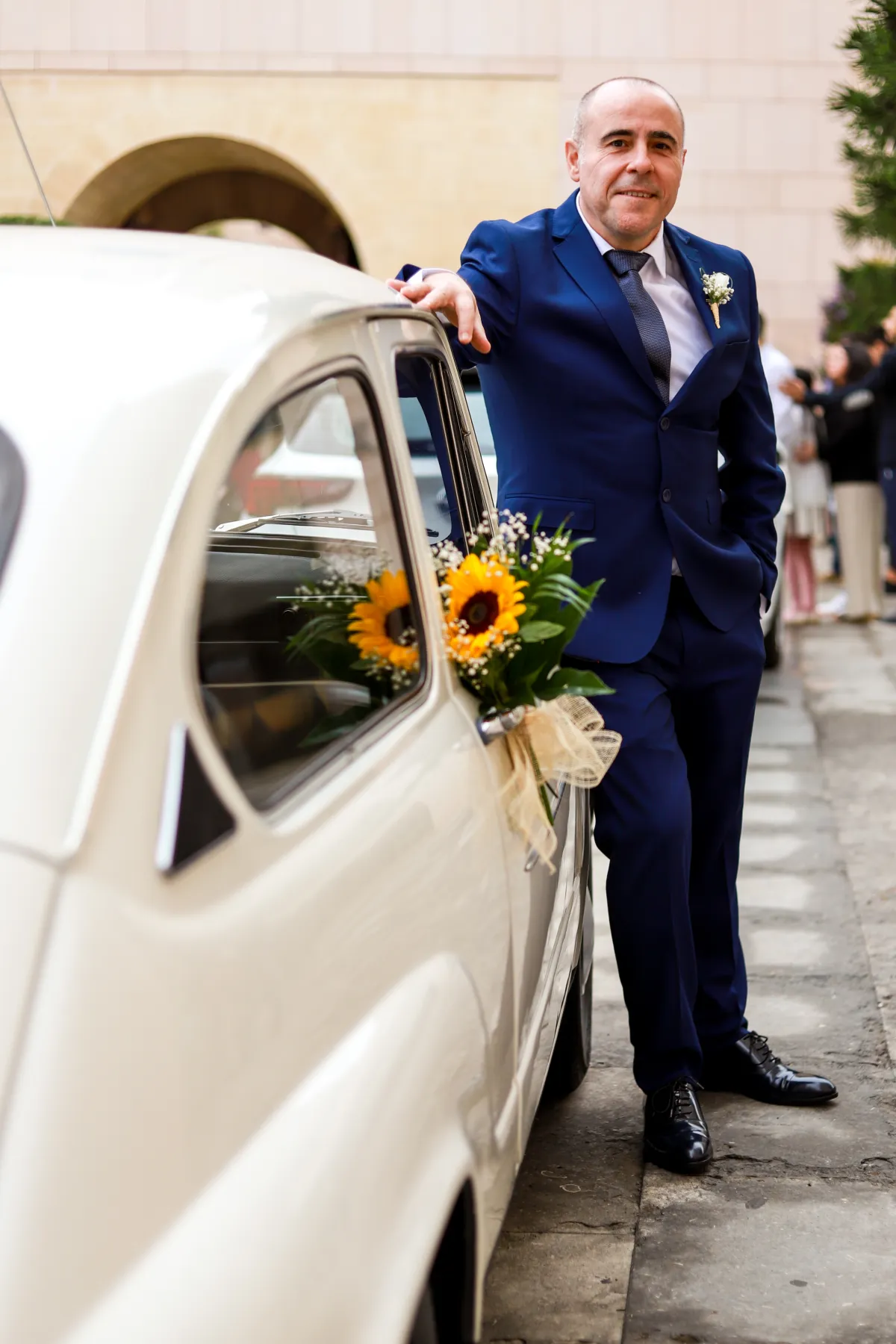Llegada del novio junto a un coche clásico decorado con flores